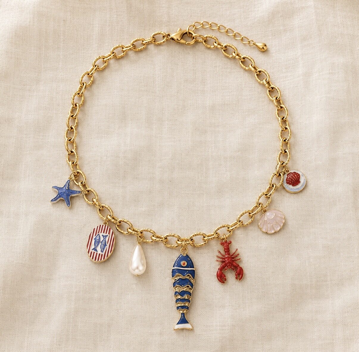 Gold charm necklace with an enamel fish, lobster, starfish and pearl