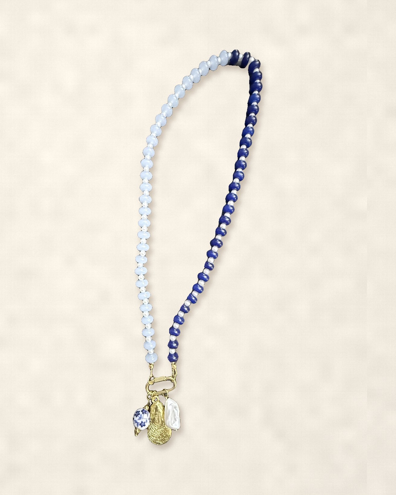 Half white, half navy beaded necklace with gold oyster, pearl and porcelain charms