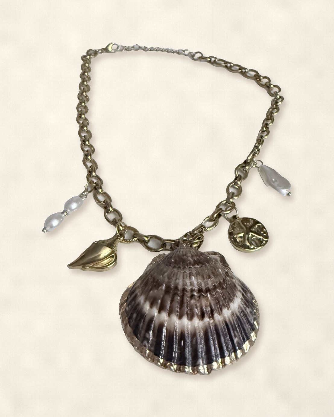 Gold chain necklace with a natural scallop shell, pearls and gold charms