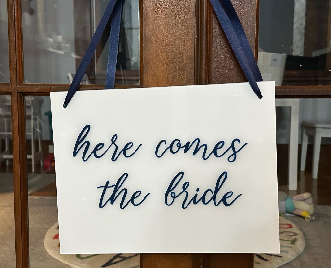 Here comes the bride acrylic sign hanging from navy ribbon