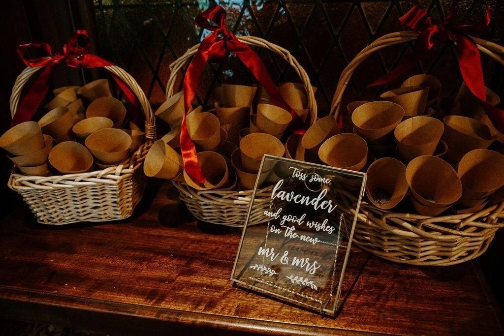Glass sign reading toss some lavender and good wishes on the new Mr and Mrs beside baskets of kraft paper cones