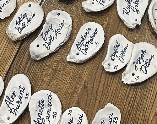 Oyster shell place cards hand-lettered with guest names and table numbers