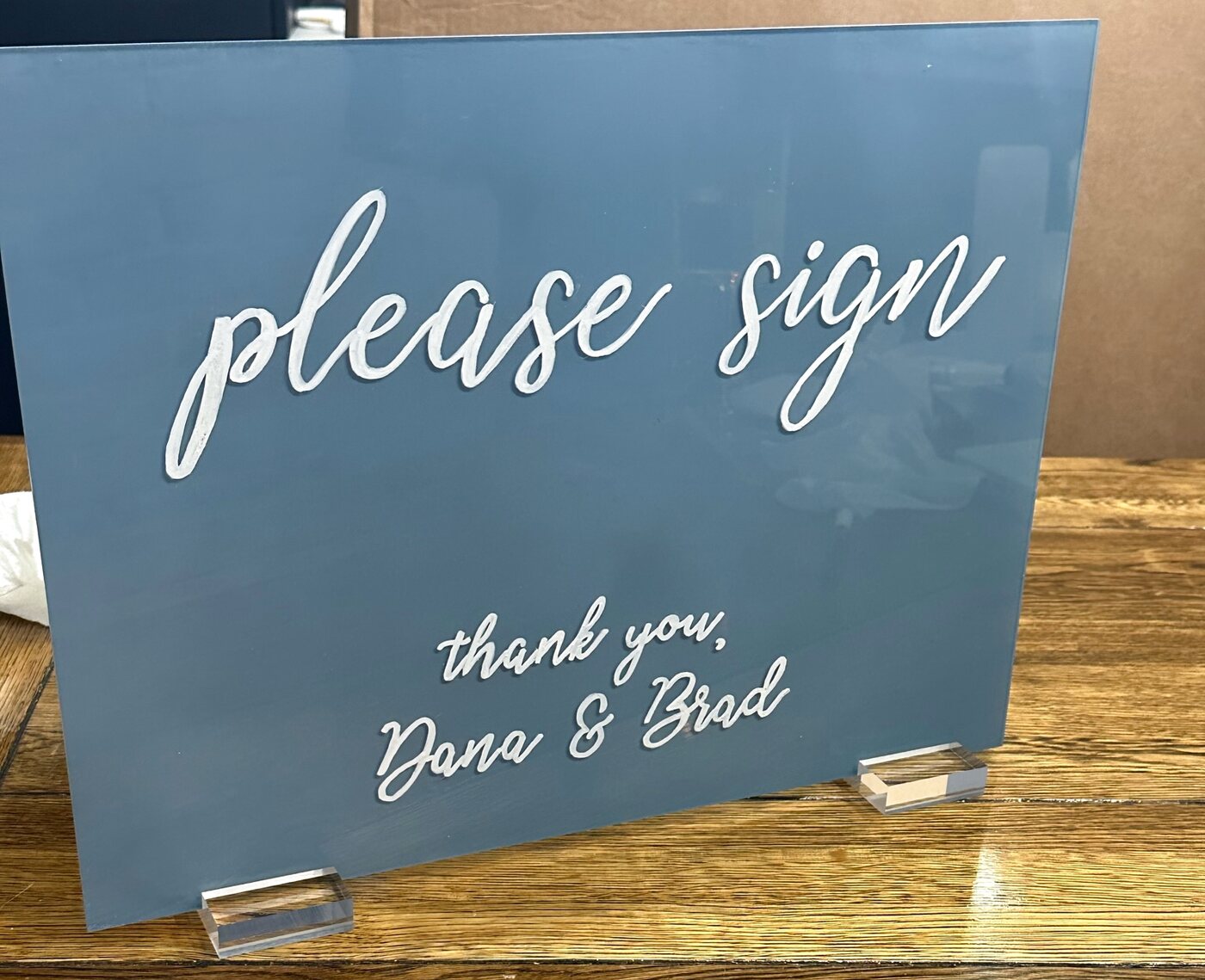 Dusty blue acrylic guestbook sign reading please sign, thank you, Dana and Brad