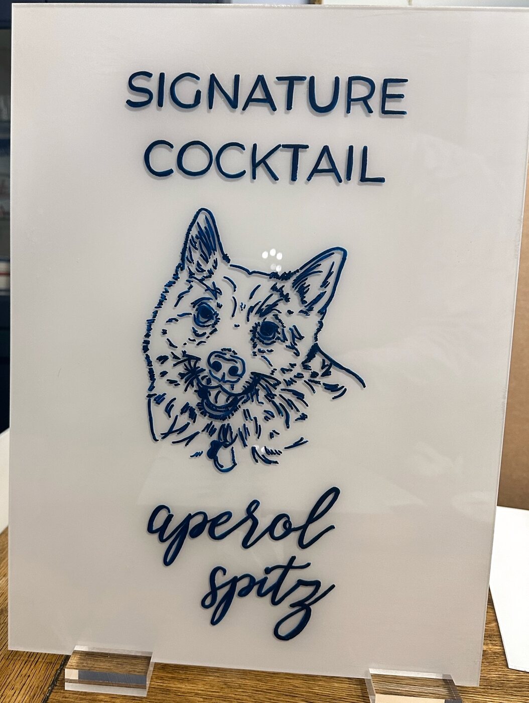 Signature cocktail sign with a hand-drawn navy dog portrait, reading aperol spitz