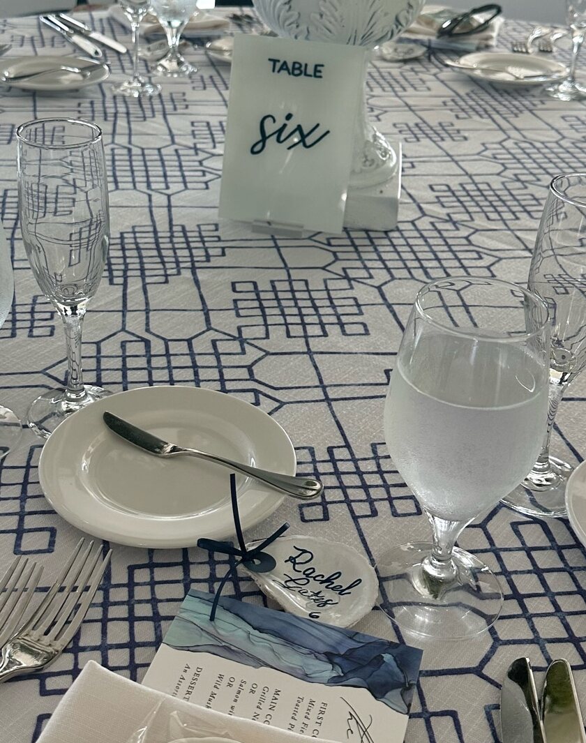 Table six number and an oyster shell place card on a blue and white wedding table