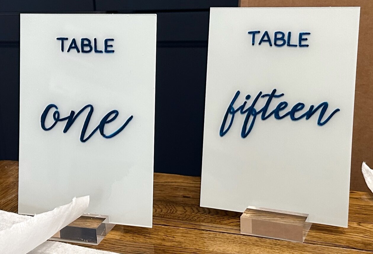White acrylic table numbers reading one and fifteen in navy script